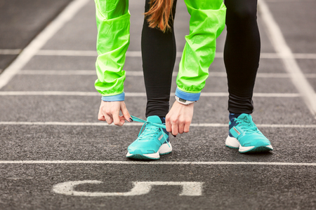 Cropped shot of a woman tying her shoelaces before running on a stadium.の写真素材