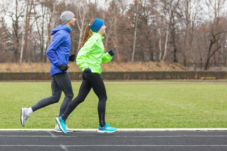 Full length shot of a young couple running on a stadium.の写真素材