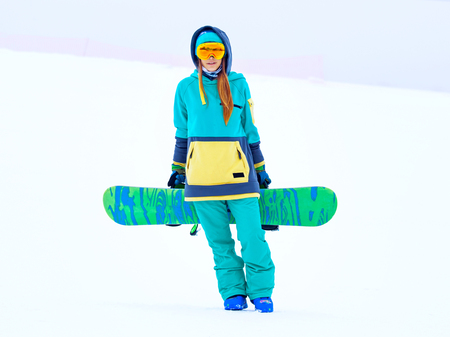 Portrait of beautiful young snowboarder girl holding snowboard.の写真素材