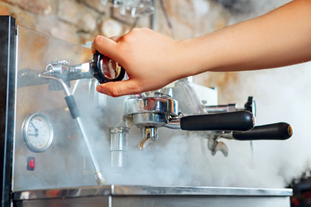 Close up of barista warming up espresso coffee machine.の写真素材