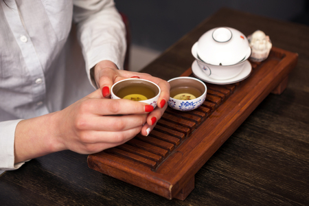 Cropped shot of woman holding traditional chinense teacup with oolong green tea.の写真素材