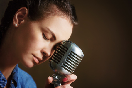 Beautiful woman singing holding retro microphone.の写真素材