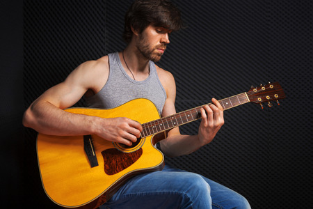 Handsome rock guitarist practicing in sound studio.の写真素材