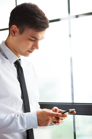 Portrait of young handsome businessman using his phone.の写真素材