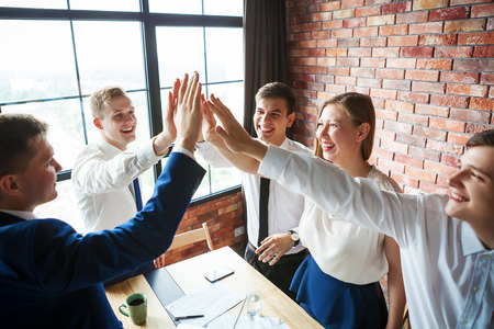 Group of happy young business team celebrating and high fiving each other.の写真素材