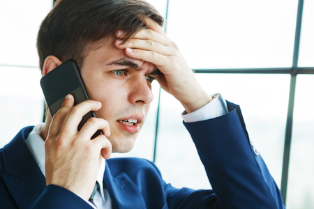 Bad news. Portrait of young handsome businessman talking on the phone.の写真素材