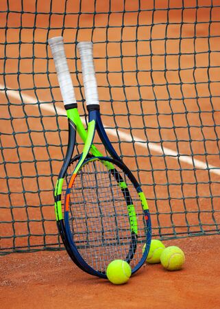 Two tennis rackets and balls leaned against the net.の写真素材