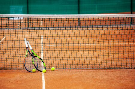 Two tennis rackets and balls leaned against the net.の写真素材