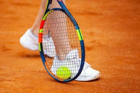 Female tennis player legs in tennis shoes standing on a clay court close up.の写真素材
