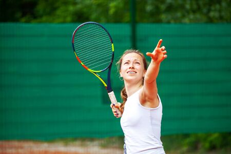 Young beautiful female tennis player serving.の写真素材