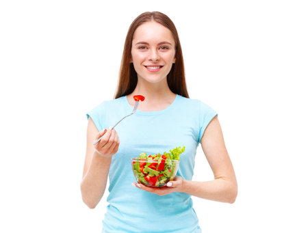 Portrait of a fit healthy woman eating a fresh salad isolated on white background. Dieting and healthy eating concept.の写真素材