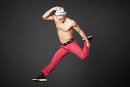 Young male professional dancer jumping in studio isolated on gray background.の写真素材