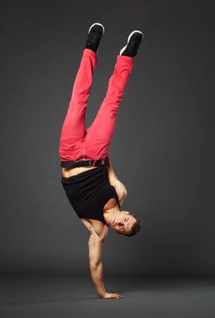 Young male professional dancer B-boying in studio isolated on gray background.の写真素材