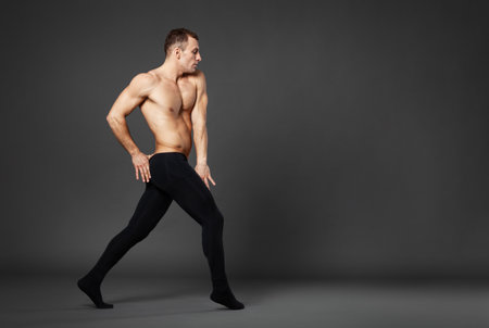 Full body portrait of a young ballet dancer dancing against a gray background.の写真素材