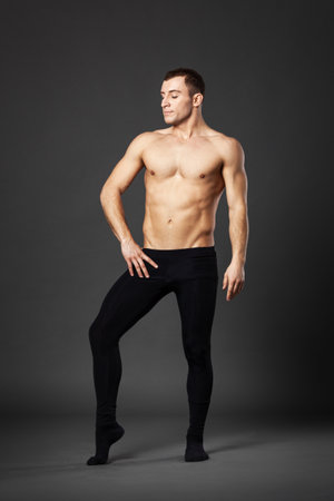 Full body portrait of a young ballet dancer posing against a gray background.の写真素材