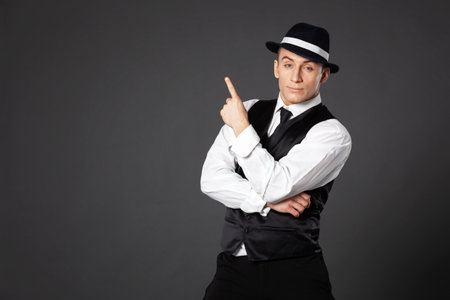 Confident young man posing in gangster style suite. Studio isolated on gray background.の写真素材