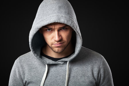 Studio portrait of cool looking young guy in sportswear standing against dark gray background.の写真素材