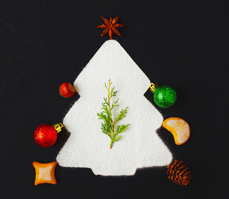 Christmas background with powdered sugar as Christmas tree, ginger cookies, anise and Christmas decorations on dark background. Creative cristmas concept. Top view, copy space, text placeの写真素材