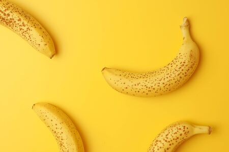 Fresh yellow ripe bananas on yellow background pattern, top viewの写真素材