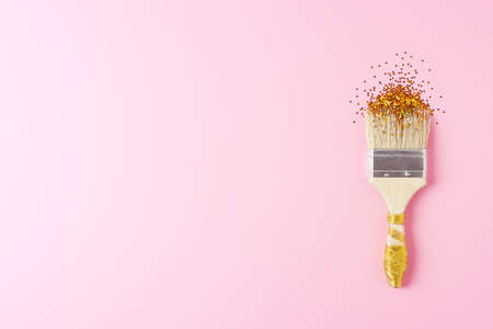 Paint brush with golgen confetti on pink background. Christmas, winter, new year concept. Flat lay, top view, copy spaceの写真素材