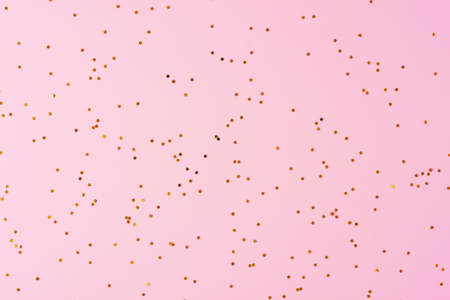 Golden confetti on pink background. Christmas, winter, new year texture. Flat lay, top viewの写真素材