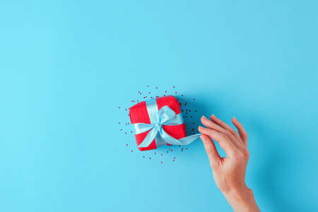 Woman hand opens a gift. Christmas, new year, holiday concept. Banner, greeting card mockup. Blue...