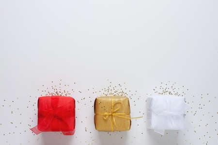 Different colored gifts with confetti on white background. Christmas or holiday concept. Flat lay, copy spaceの写真素材