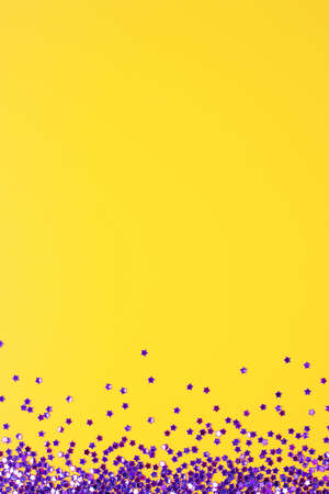 Violet confetti on yellow. Colorful Christmas or holiday backgroundの写真素材