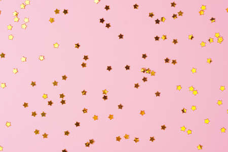 Golden confetti on pink. Colorful Christmas or holiday background