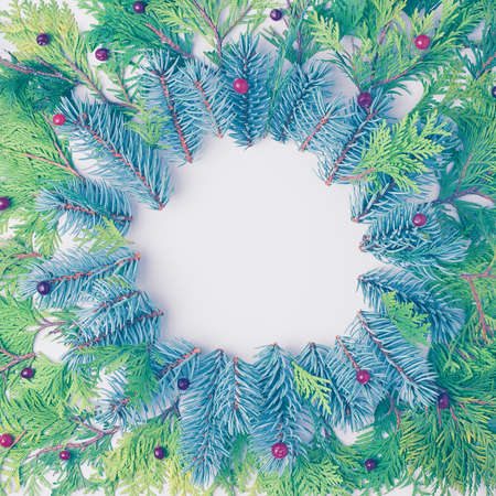Christmas frame made from blue and green fir tree branches and red berries. Christmas or holiday concept. Flat lay, copy spaceの写真素材