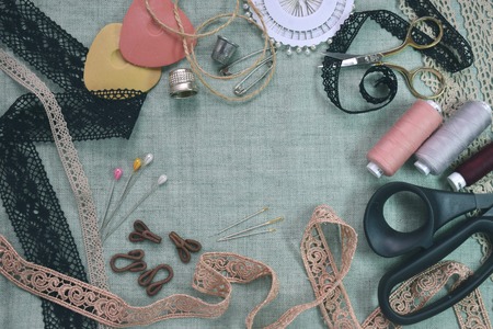 Sewing scene table flat lay composition. Threads, lace, pins, scissors, tape, reel, cloth. Pastel colors linen fabric text space. Top view banner templateの写真素材
