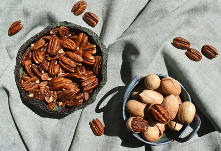 Pecan in ceramic bowl. Unpeeled nuts in shell deep green rustic porcelain. Organic raw healthy diet. Top close up view linen fabric nobodyの写真素材