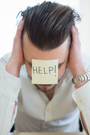 businessman frustrated with a post-it help in his face