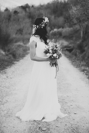portrait of bohemian and hippie bride in countryside, with rustic bouquet and crownの写真素材