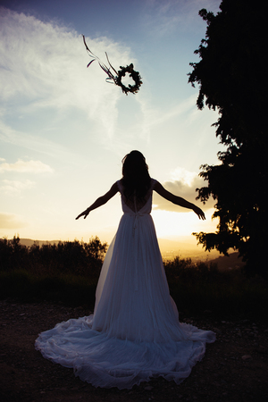 silhouette of bride in a landscape, with a flower crown in airの写真素材