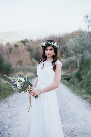 portrait of bohemian and hippie bride in countryside, with rustic bouquet and crownの写真素材