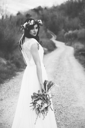 portrait of bohemian and hippie bride in countryside, with rustic bouquet and crownの写真素材