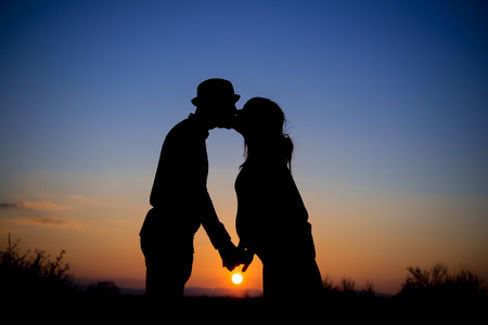 silhouette of couple, kiss, maternity, sunsetの写真素材