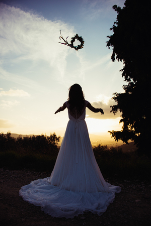 silhouette of bride in a landscape, with a flower crown in airの写真素材
