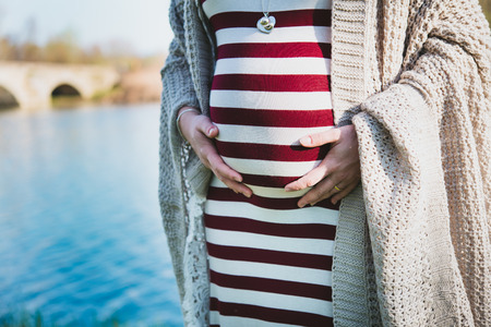 close-up of a pregnant belly, outdoor, by the riverの写真素材