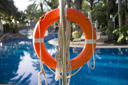 An orange rubber ring at a pool of blue waters  There are Palm trees at the surrounding areaのeditorial素材