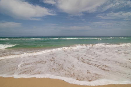 Waves breaking on the shore  The sea merges with the sky on the horizon  Some clouds at the skyの写真素材