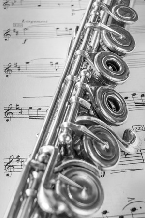 Transversal flute instrument detail, over a music sheet.の写真素材
