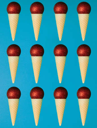 Christmas scene, pop art ornamental balls in ice cream spiral cone on blue background. New year and xmas decoration concept with copy space. Minimal coloredの写真素材