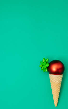 Christmas scene, ornamental balls in ice cream spiral cone on green background with ribbon. New year and xmas decoration concept with copy space. Minimal coloredの写真素材