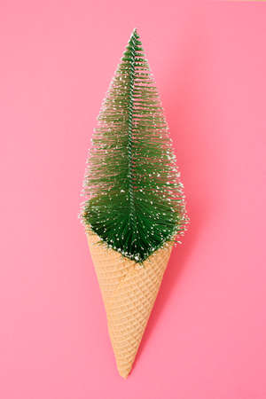 Glossy glistening Christmas three in ice cream spiral cone on pink background. Green with brown color. New year and xmas decoration concept. Minimal coloredの写真素材