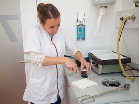 Female dental technician casting compound in a mufflesの写真素材