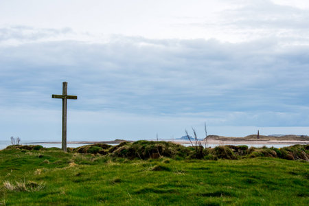 A wooden cross, on a grassy island, on the Holy Island of Lindisfarneの写真素材