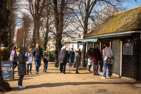 People waking through Dane John Gardens, Canterbury, Kent, on a bright spring day.