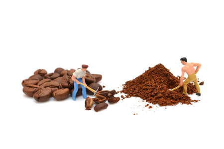 Miniature people grind coffee. Little people break coffee beans. Ground coffee. Macro. Figures of people. Statuette. Handful of coffeeの写真素材